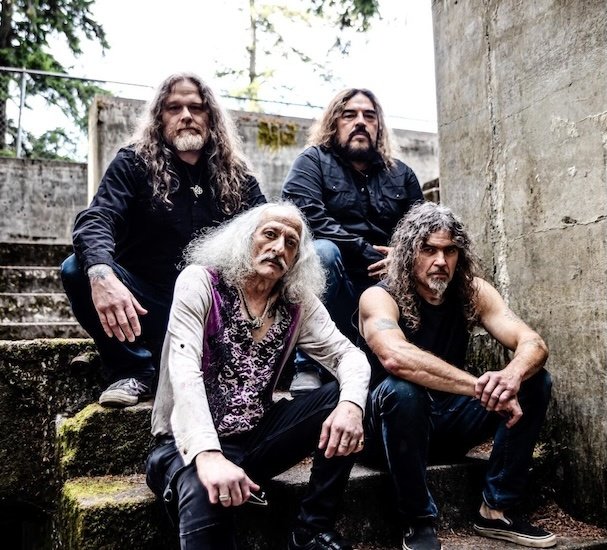 Pentagram band portrait: four members seated on outdoor stone steps