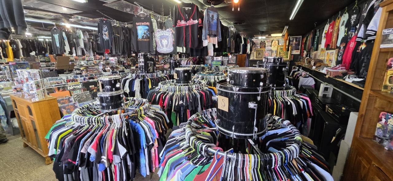 A wide view of The Freak with clothing racks, drums and records